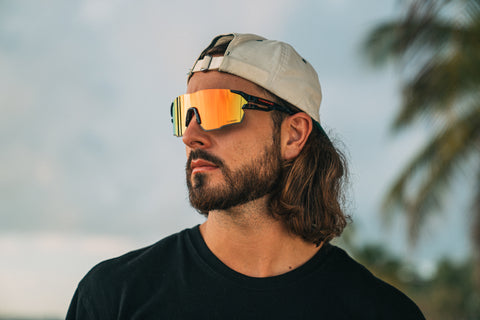 a man wearing Torege wrap-around sunglasses standing by the beach looking at the distance