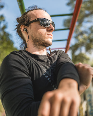 a man stretching his shoulder wearing Torege sunglasses before workout in an outdoor setting
